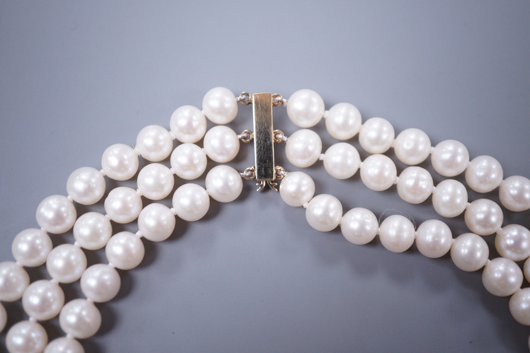 A modern triple strand cultured pearl set choker necklace, with 375 yellow metal clasp, 43cm.